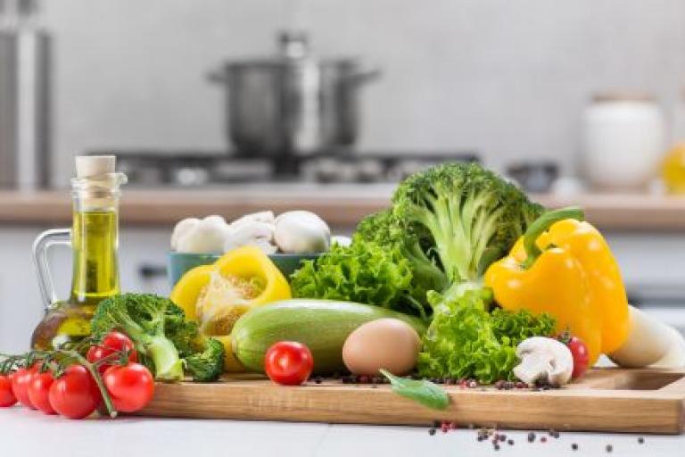 A variety of vegetables on a chopping board, in a kitchen.