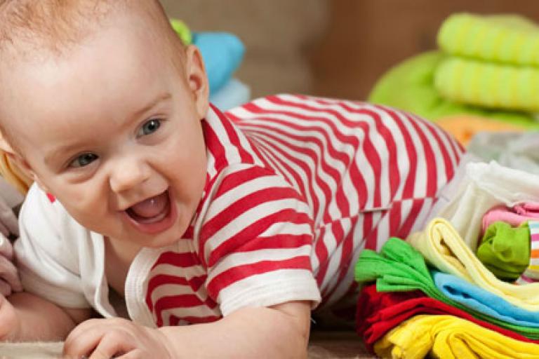 smiling baby crawling amongst colourful cloth nappies
