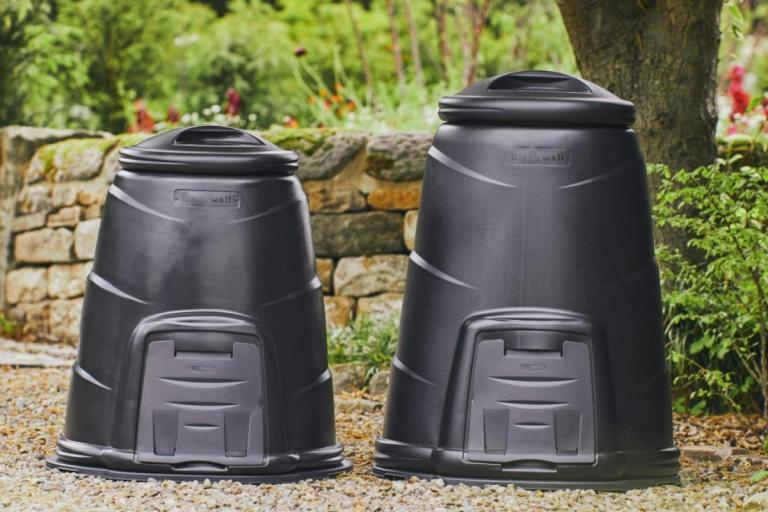 Two black compost bins in a garden.