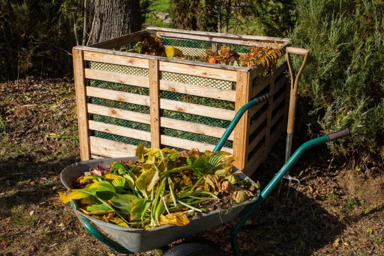 Compost bin made of pallets with a wheelbarrow.