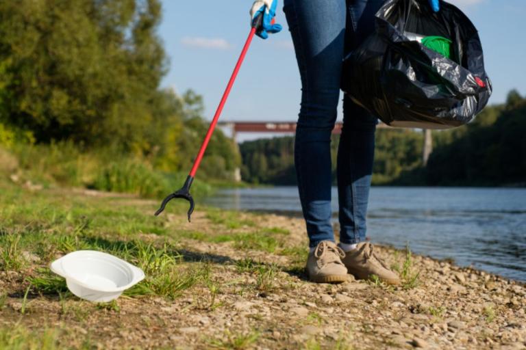 Person litter picking beside a river.