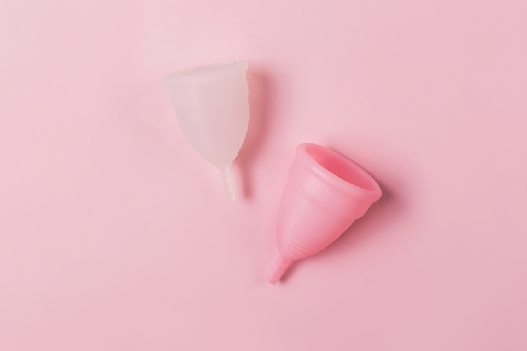 Clear and pink menstrual cups laid on pink background 