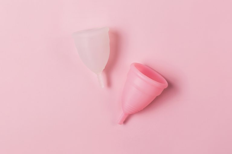 Clear and pink menstrual cups laid on pink background.