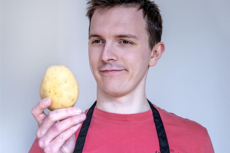 Man looking at a potato with a confused look