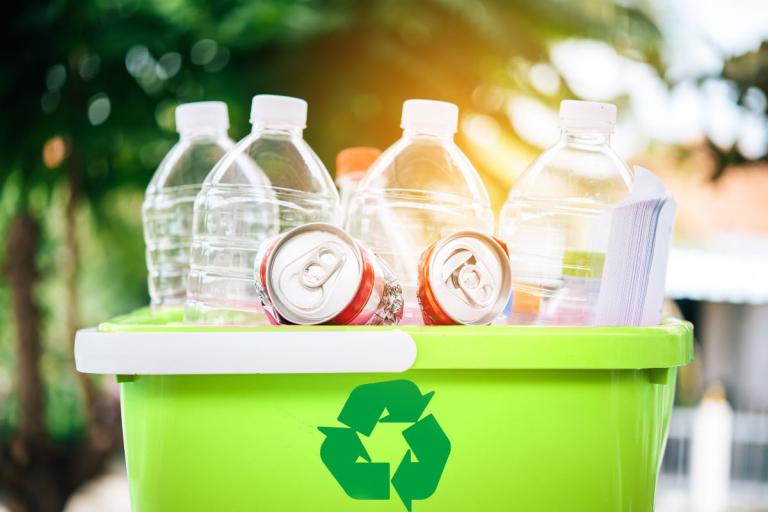 Green recycling box filled with plastic bottles and cans.