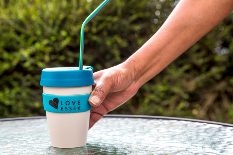 A reusable Love Essex cup being picked up off a table