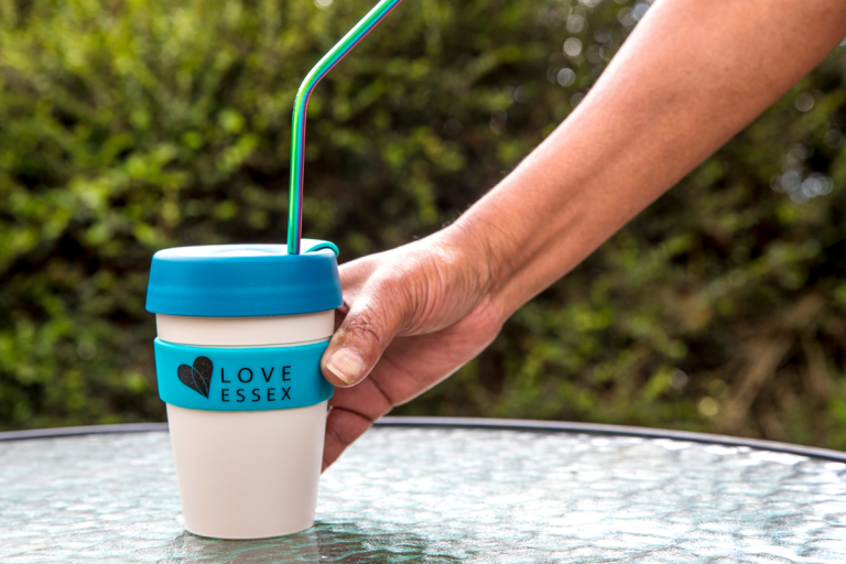 A reusable Love Essex cup being picked up off a table.