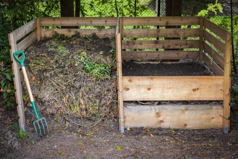 A home made wooden compost bin in garden.