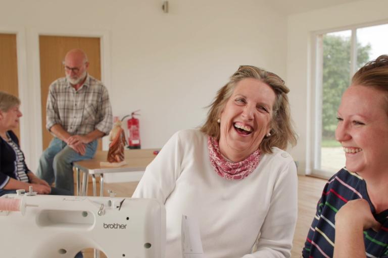 A group of four people talking and laughing at a repair cafe.