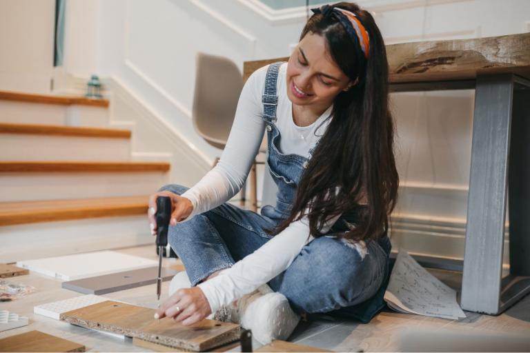 A woman sitting on the floor doing DIY. 