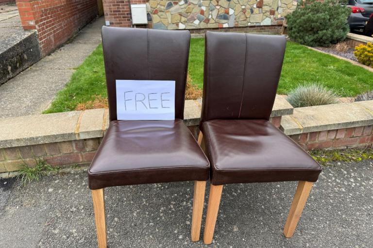 Two chairs on the pavement outside a house with a 'Free' sign.