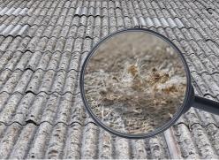 Roof tiles with a magnifying glass showing a close-up image of asbestos fibres