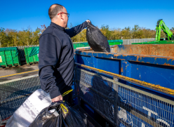 Man putting black ban into a container at a recycling centre