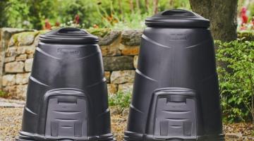 Two black compost bins in a garden.