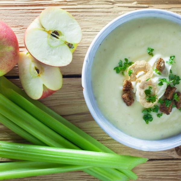 Bowl of soup with apples and celery to the side.