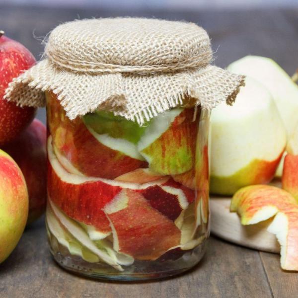 Jar of apple scrap vinegar surrounded by apples.
